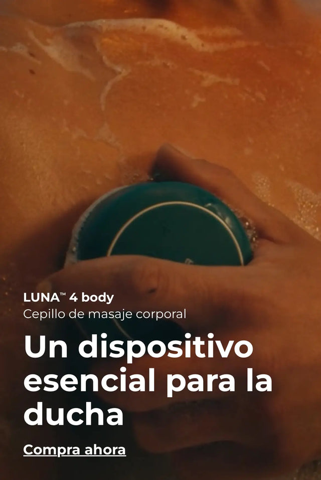 Primer plano de una persona en la ducha usando el dispositivo de masaje corporal azul y verde oscuro 'LUNA™ 4 body' sobre su piel. El texto promocional dice: 'LUNA™ 4 body. Cepillo de masaje corporal. Un dispositivo esencial para la ducha. Compra ahora'.