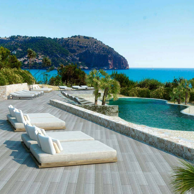 Tumbonas de lujo junto a una piscina infinita con vistas al mar Mediterráneo y montañas al fondo, rodeadas de vegetación tropical. Tumbonas de lujo junto a una piscina infinita con vistas al mar Mediterráneo y montañas al fondo, rodeadas de vegetación tropical.