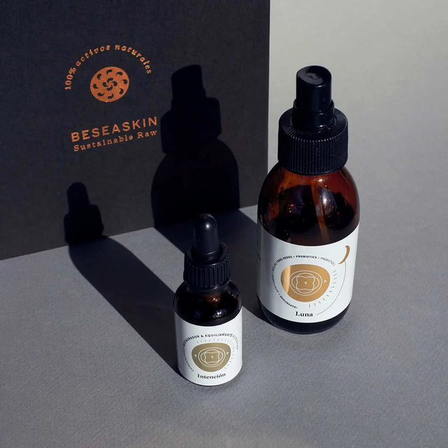 Envase de serum facial Elixir Intención y de aceite corporal Elixir Luna de Smell The Planet, 100% orgánicos con propiedades antioxidantes e hidratantes sobre superficie gris. Envase de serum facial Elixir Intención y de aceite corporal Elixir Luna de Smell The Planet, 100% orgánicos con propiedades antioxidantes e hidratantes sobre superficie gris.