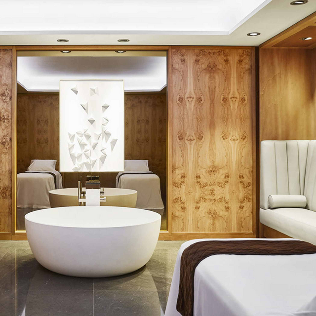 Cabina de spa en el Hotel Four Seasons Madrid, con decoración elegante de madera, camas de tratamiento y luz suave.