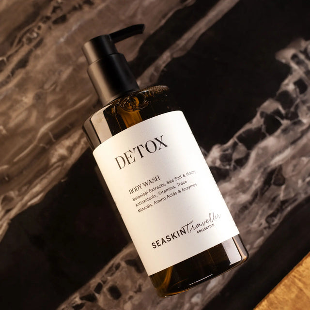 Botella con dispensador de gel de baño 'DETOX' de la colección SEASKIN Traveller. La etiqueta indica que contiene extractos botánicos, sal marina, yodo, antioxidantes, vitaminas, oligoelementos, aminoácidos y enzimas. Detox Body Wash | Activated Charcoal and Green Tea
