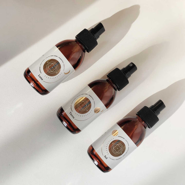 Envases de los elixires corporales Luna, Sol y Tierra de Smell The Planet, 100% orgánicos con hierbas tónicas curativas y probióticos, sobre superficie blanca