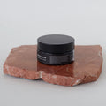 Bálsamo limpiador facial Bebalm  sobre piedra roja.