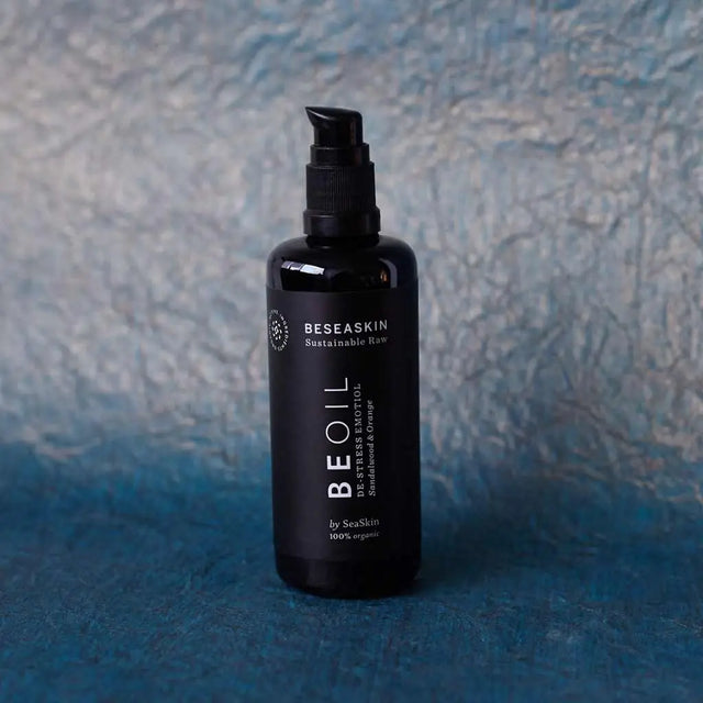 Envase de aceite corporal relajante de Beseaskin, 100% orgánico a base de Sándalo y Naranja con fondo azul oscuro.