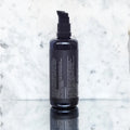 Envase de aceite facial y corporal regenerador de Beseaskin, 100% orgánico a base de Coco y Aloe Vera con un fondo de mármol.