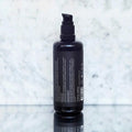 Envase de aceite corporal antiaging de Beseaskin, 100% orgánico a base de Lavanda y Palo de Rosa con fondo de mármol.