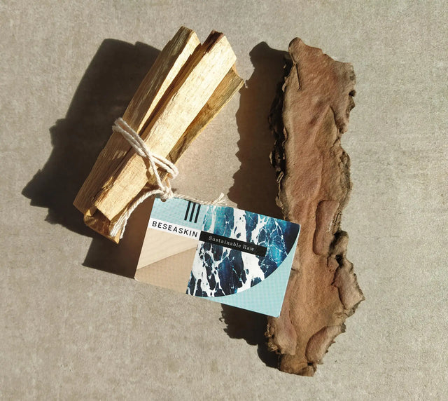Palo Santo, purificador de energías, envuelto en una cuerda con etiqueta de SeaSkin Life sobre superficie gris.