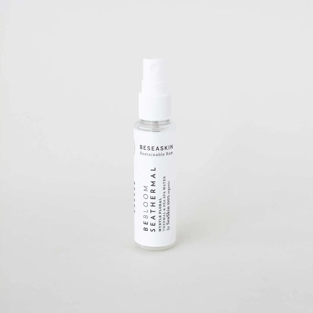 Botella pulverizadora pequeña y transparente (formato de viaje) de 'BE THERMAL' de la marca SEASKIN, con una etiqueta blanca y negra. El envase se presenta sobre un fondo blanco liso.