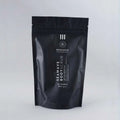 Envase de bálsamo exfoliante corporal circulatorio de Beseaskin, 100% orgánico a base de Lemongrass y Geranio con fondo gris.