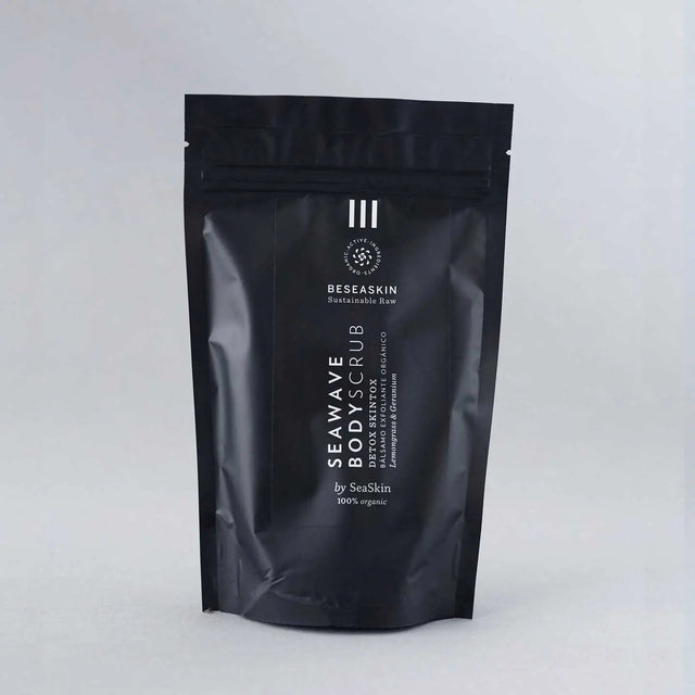 Envase de bálsamo exfoliante corporal circulatorio de Beseaskin, 100% orgánico a base de Lemongrass y Geranio con fondo gris.