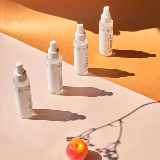 Cuatro envases de brumas florales de Beseaskin de Geranio, Rosa, Lavanda y Neroli, 100% orgánicas con Agua Termal y Concentrado de Posidonia, con un fondo naranja y rosa.