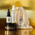 Envases de Bebalm Face Cleanser (limpiador), Bebloom Seathermal Lavanda (calmante) y Elixir Ío (hidratante y regenerador), con bolsa de tela de Seaskin Life sobre superficie dorada.