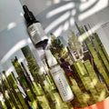Envases de bruma floral facial de Mirto reafirmante y aceite facial Ío hidratante y regenerador, 100% orgánicos sobre revista con foto de naturaleza.