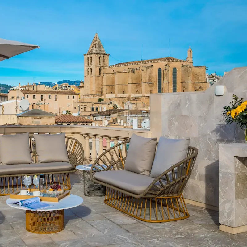 Terraza con muebles de exterior y vista panorámica del casco antiguo de Palma de Mallorca con la catedral de fondo.