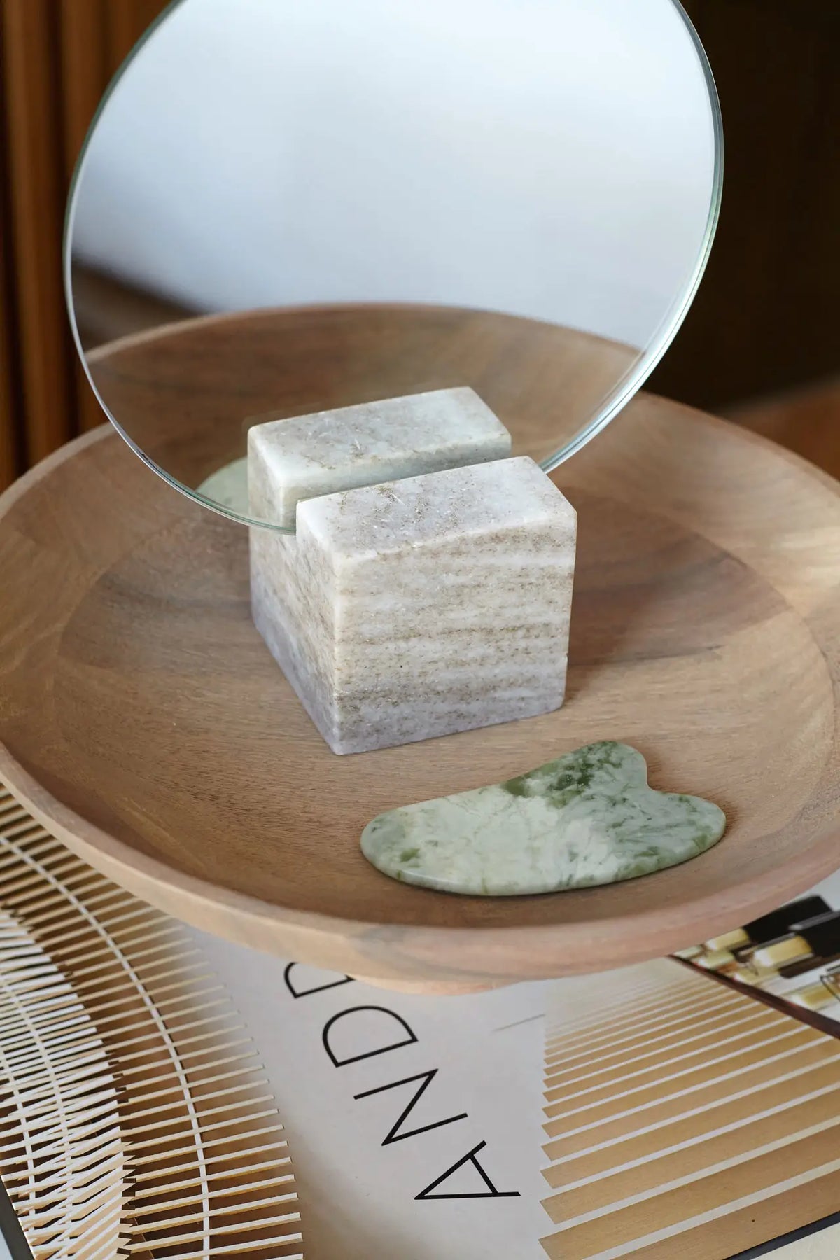 Gua Sha de jade verde natural herramienta facial para masaje antiedad en bandeja de madera.