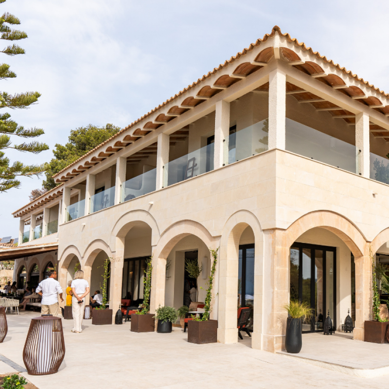 Fachada principal del complejo Santa Ponsa con arquitectura mediterránea, arcos elegantes y terraza superior con barandilla de cristal.