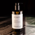 Botella ámbar con dispensador de bomba de jabón de manos 'PURIFY' de la colección SEASKIN Traveller. La etiqueta menciona que contiene extractos botánicos, sal marina, miel, antioxidantes, vitaminas, oligoelementos, aminoácidos y enzimas.