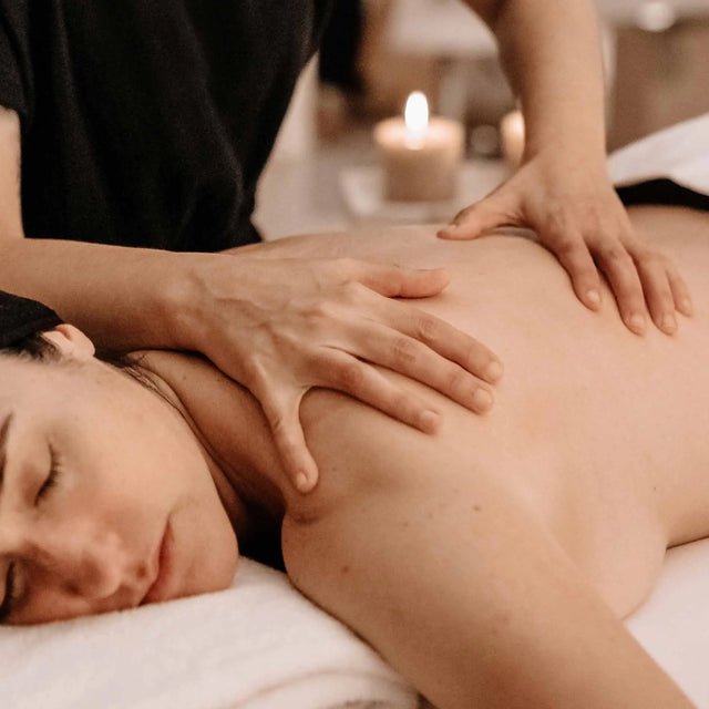 Masaje de desintoxicación (Detox) en la espalda con movimientos relajantes, en un spa con luz tenue y velas encendidas.