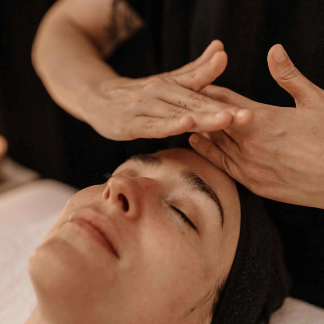 Mujer recibiendo un tratamiento facial energy relajante. Primer plano de manos profesionales aplicando un masaje facial en la frente como parte de una sesión de cuidado de la piel y spa.