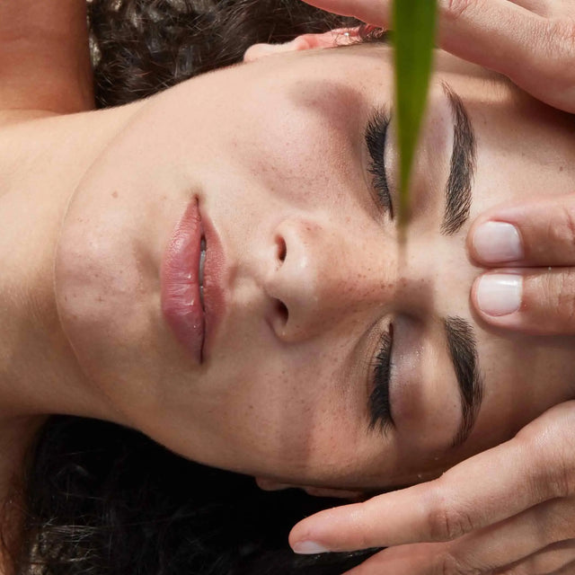 Primer plano de mujer recibiendo un masaje profesional aplicando presión en la frente y entrecejo para relajación facial y cuidado de la piel natural