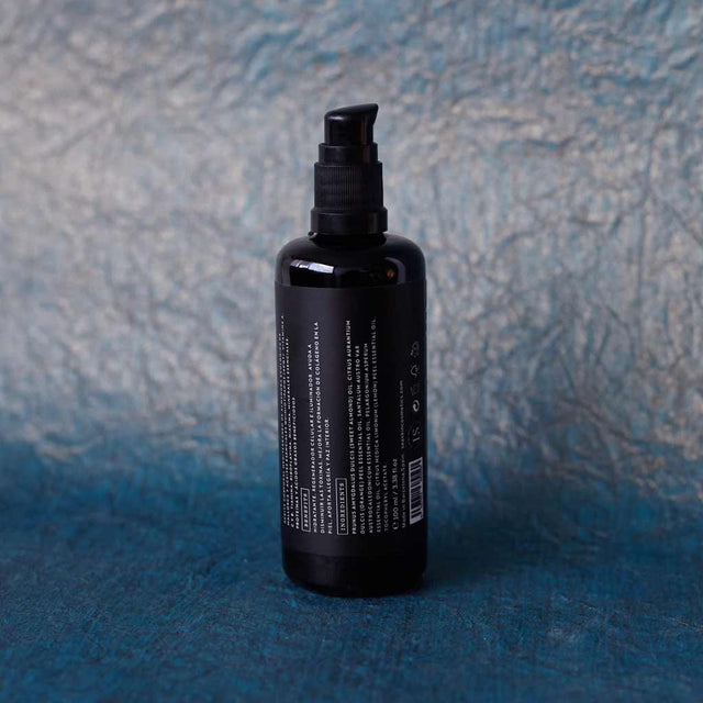 Envase de aceite corporal relajante de Beseaskin, 100% orgánico a base de Sándalo y Naranja con fondo azul oscuro.