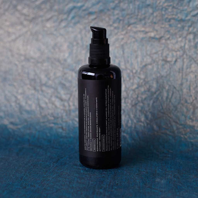 Envase de aceite corporal reafirmante de Beseaskin, 100% orgánico a base de Lemongrass y Geranio con fondo azul oscuro.