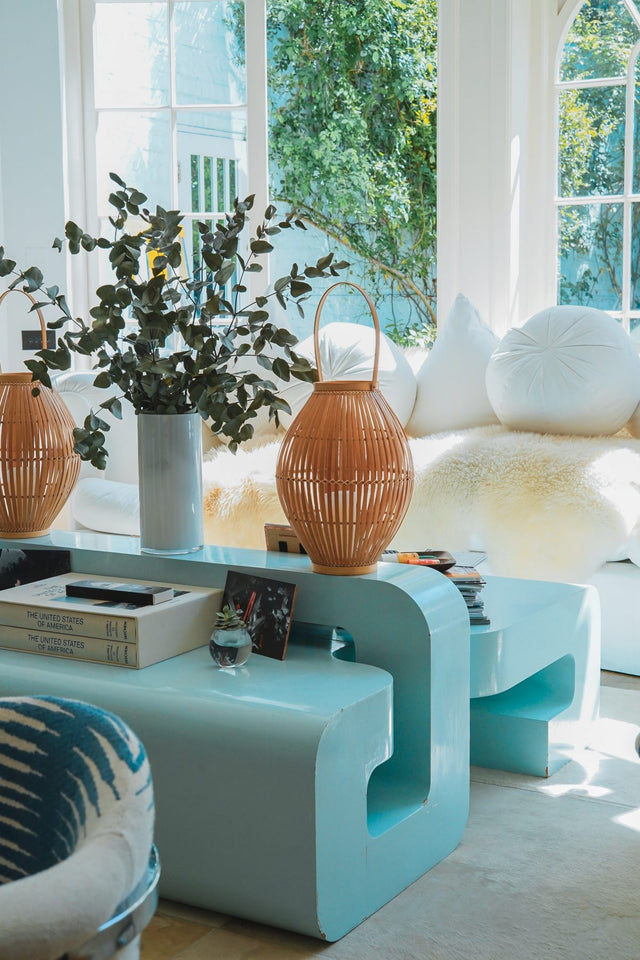 Salón de una casa con muebles decorativos con tonos azules pastel y blancos y un ventanal que lleva a un jardín