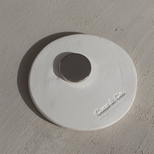 Parte trasera de imán de barro redondo color blanco con sello de la marca Cons & Co