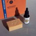Envase de Elixir Ío, aceite facial hidratante de Smell The Planet, junto a Jabón Vegetal Artesanal regenerador de SeaSkin sobre superficie gris