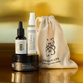 Envases de Bebalm Face Cleanser (limpiador), Bebloom Seathermal Lavanda (calmante) y Elixir Ío (hidratante y regenerador), con bolsa de tela de Seaskin Life sobre superficie dorada